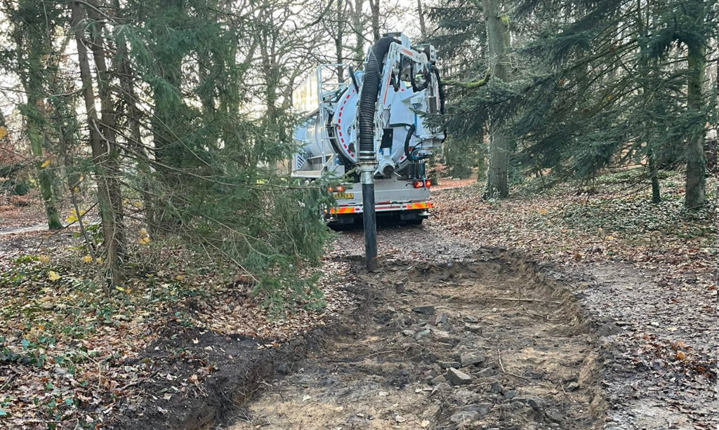 Wouters-zuigwagen in een bosrijke omgeving tijdens grondwerken en technische ondersteuning op locatie.