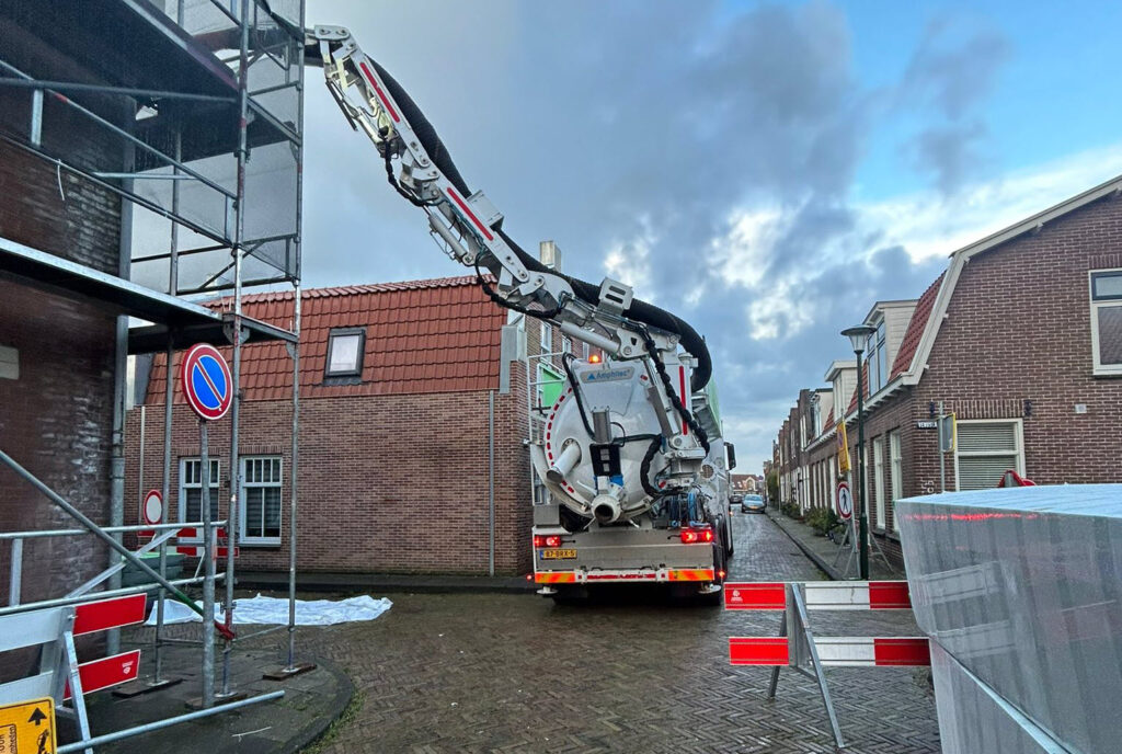 Wouters-zuigwagen in een woonstraat tijdens bouwondersteuning en werkzaamheden op hoogte.